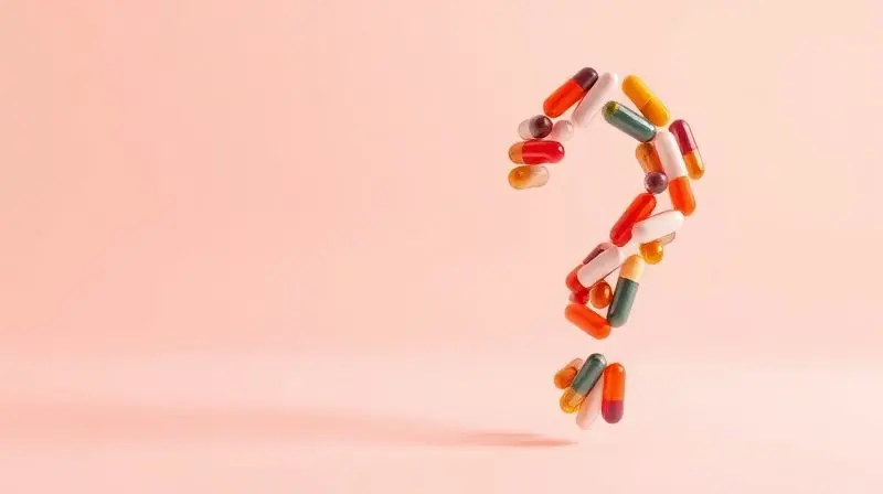 Símbolo de interrogação com cápsulas de multivitamínicos representando dúvidas comuns.